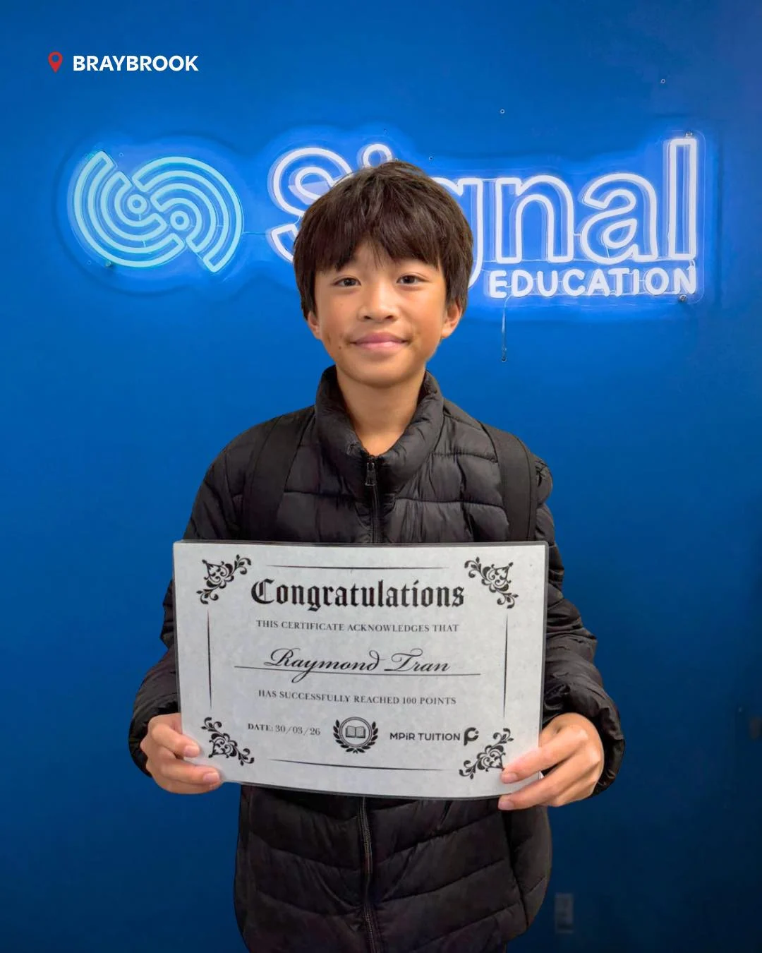 A Signal Education student holding a 100-point achievement certificate